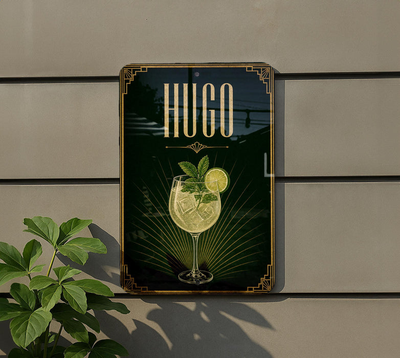 A sign for a bar called "HUGO" with a glass of a yellow drink and a lemon slice, set against a green background with a decorative border.