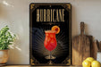 A decorative sign with the word "HURRICANE" prominently displayed, featuring an illustration of a vibrant red cocktail garnished with a slice of orange.