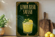 A framed poster with a picture of a lemon basil smash drink, accompanied by the text "Lemon Basil Smash" on a green background with gold trim.