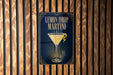 A sign for a lemon drop martini is displayed on a wooden wall.