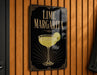 A sign for a lime margarita is hanging on a wooden wall.