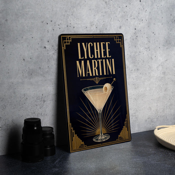 A framed image of a lychee martini cocktail, with a decorative border and a glass illustration, is displayed on a gray countertop.
