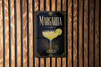 A sign for Margarita cocktail is displayed on a wooden wall.