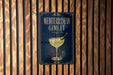 a sign for a Mediterranean cocktail called the Mediterranean Gimlet, which is displayed on a wooden wall.