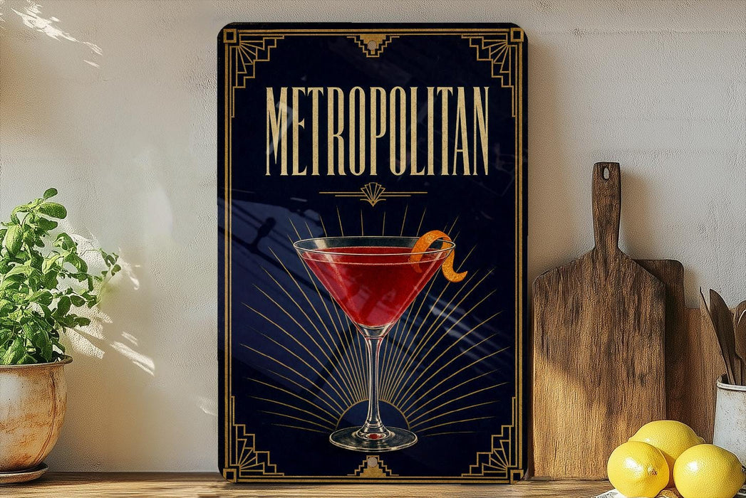 a poster or sign with the word "METROPOLITAN" prominently displayed, along with an illustration of a martini glass containing a red drink and a lemon twist. The poster is set against a dark background with a decorative border, and there are some potted plants and kitchen utensils visible in the foreground.