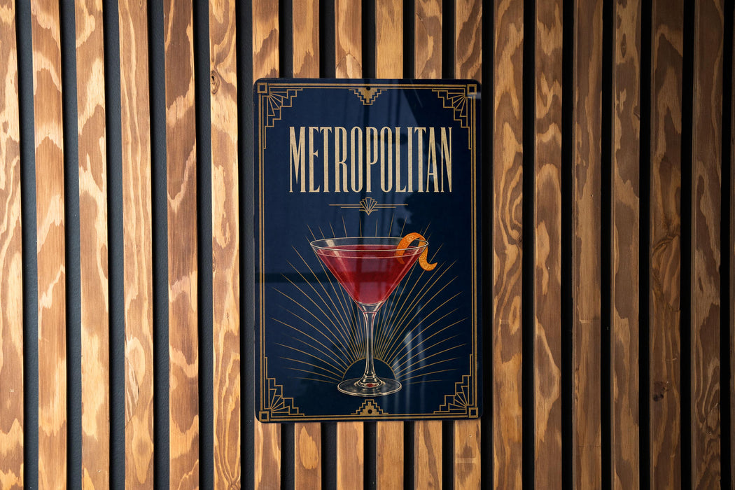 A poster for "Metropolitan" cocktail, featuring a martini glass with a cocktail in it, is displayed on a wooden wall.