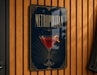 A metallic sign with a stylized design hangs on a wooden wall, featuring a martini glass and the word "METROPOLITAN" prominently displayed.