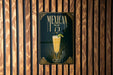 A poster with the text "MEXICAN 75" and an illustration of a drink, displayed on a wooden wall.