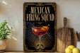 A decorative sign for a "Mexican Firing Squad" cocktail, featuring a glass of red liquid with a lemon twist, is displayed on a wooden surface next to a wooden cutting board and a potted plant.