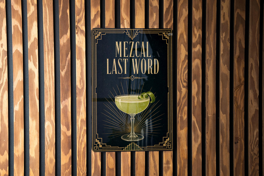 a poster with the text "MEZCAL LAST WORD" and an illustration of a cocktail glass with a lime on the poster.