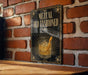 A sign with the text "MEZCAL OLD FASHIONED" and an illustration of a cocktail glass with a lemon peel.