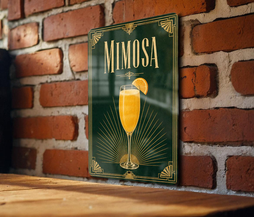 A framed poster of a mimosa cocktail is displayed on a brick wall, with a wooden table below it.