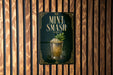A sign for a mint smash cocktail is displayed on a wooden wall.