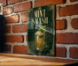 A sign with the text "MINT SMASH" and an illustration of a mint-flavored drink in a glass, mounted on a brick wall.