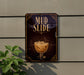 a sign that reads "MUD SLIDE" with an illustration of a glass containing a beverage, possibly a cocktail or a milkshake, on it.
