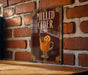 A sign for "Mulled Cider" is displayed on a brick wall, featuring an illustration of a glass of mulled cider with an orange slice.