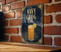 A decorative sign with the text "NAVY GROG" and an illustration of a cocktail is displayed on a brick wall.