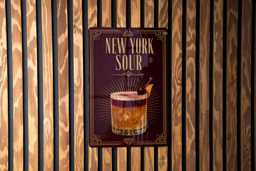 A sign for "New York Sour" cocktail is displayed on a wooden wall.