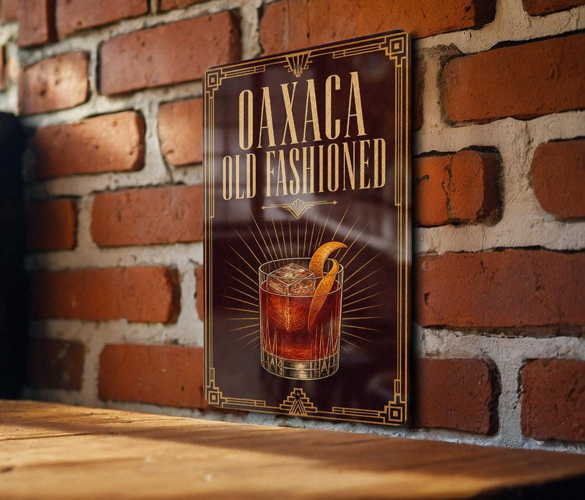 a sign for "Oaxaca Old Fashioned" cocktail, which is displayed on a brick wall.