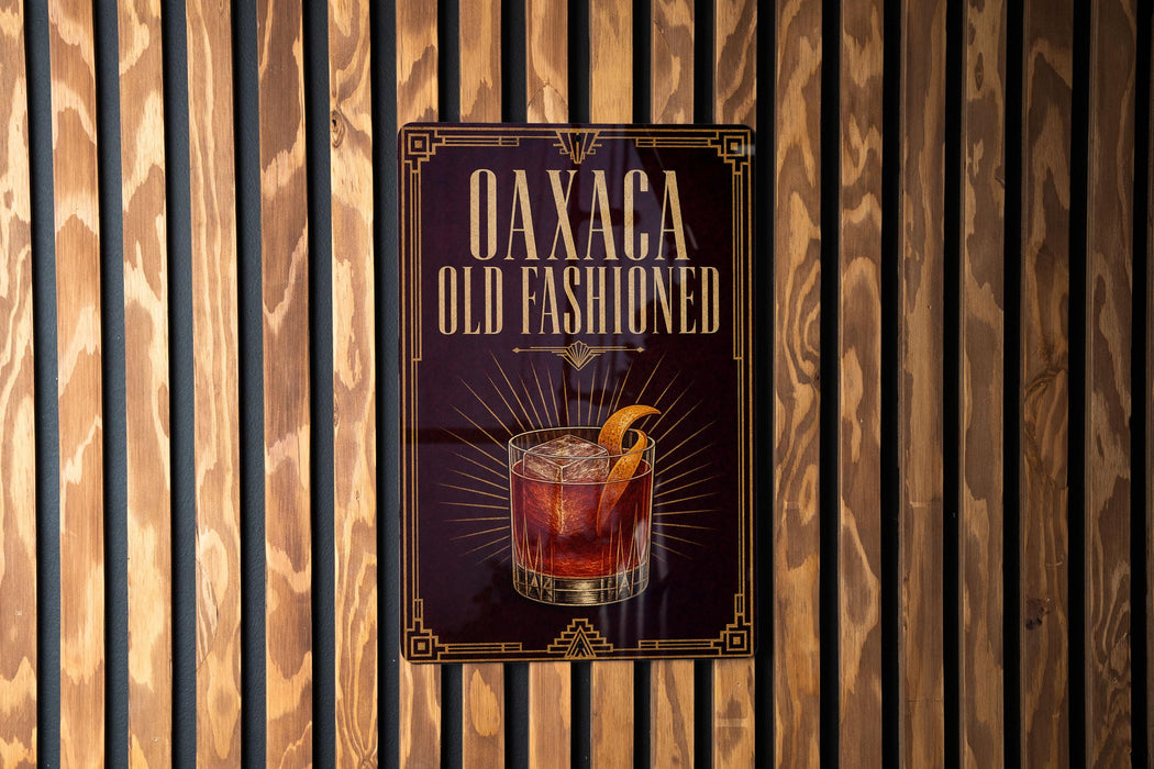 a sign for "Oaxaca Old Fashioned", which is displayed on a wooden wall.
