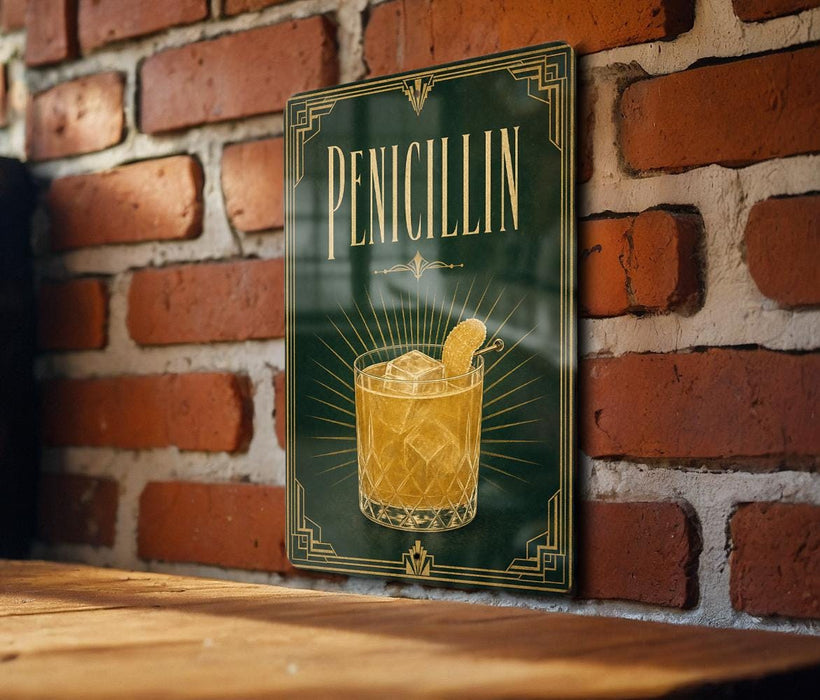 A framed poster of a cocktail glass with a lemon slice, mounted on a brick wall.