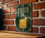 A framed poster of a cocktail glass with a lemon slice, mounted on a brick wall.