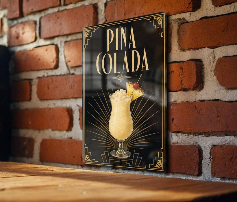 A framed poster of a Pina Colada cocktail is displayed on a brick wall.