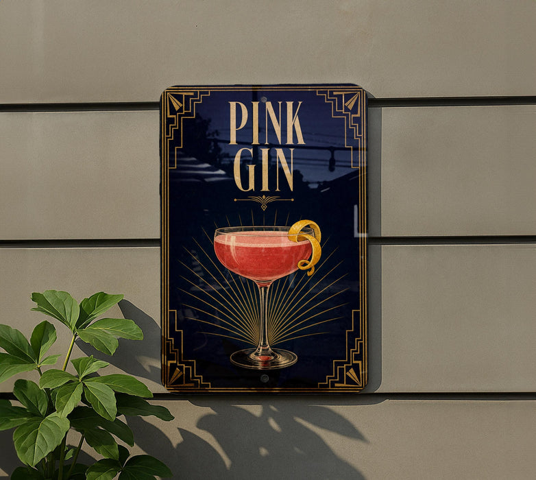 A sign for a pink gin cocktail is displayed on a wall, with a plant visible to the left.