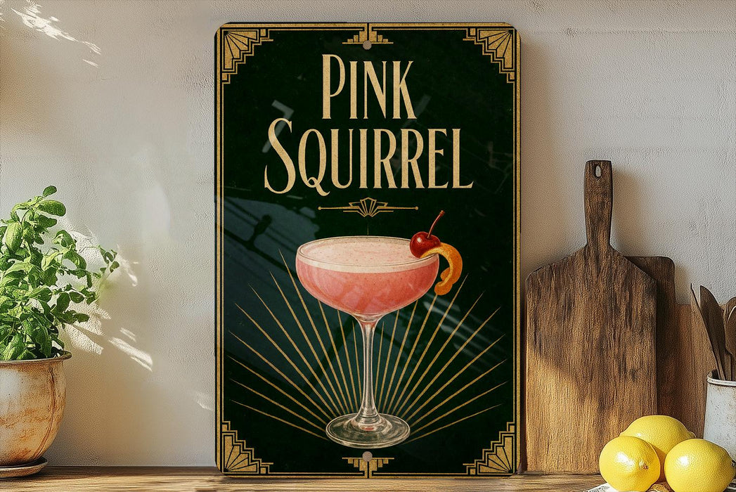 A framed poster of a pink cocktail with a cherry on top, displayed on a wall next to a wooden cutting board and a potted plant.