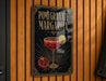 A decorative sign for a pomegranate margarita cocktail, featuring a glass of the drink and garnished with pomegranate slices and a lemon wedge.