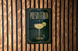 A sign for "Presbyterian" cocktail is displayed on a wooden wall.