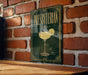 A sign with the word "PRESBYTERIAN" and an illustration of a cocktail glass is displayed on a brick wall.