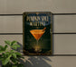 A sign advertising a pumpkin spice martini is displayed on a wall, with a plant visible to the left.