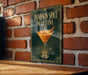 A sign for a pumpkin spice martini is displayed on a brick wall.