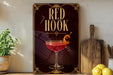 a decorative sign with the text "RED HOOK" and an illustration of a cocktail glass with a cherry and an orange slice.