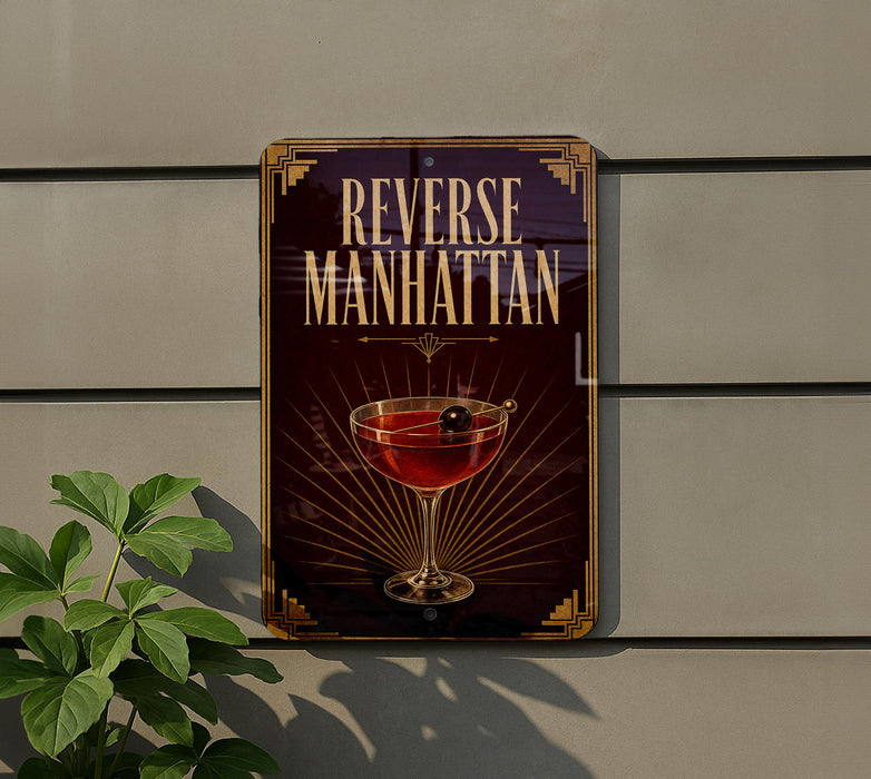 A sign for "Reverse Manhattan" cocktail, featuring a glass of red cocktail with a cherry on top, is displayed on a wall.