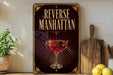a decorative sign with the text "Reverse Manhattan" and an illustration of a martini glass with a cherry on top.