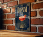 A framed poster of a cocktail called "Rossini" is displayed on a brick wall.