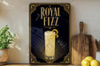 A decorative sign for Royal Fizz cocktail, featuring a glass of the drink and a lemon slice, is displayed on a wooden shelf next to a potted plant and a cutting board.