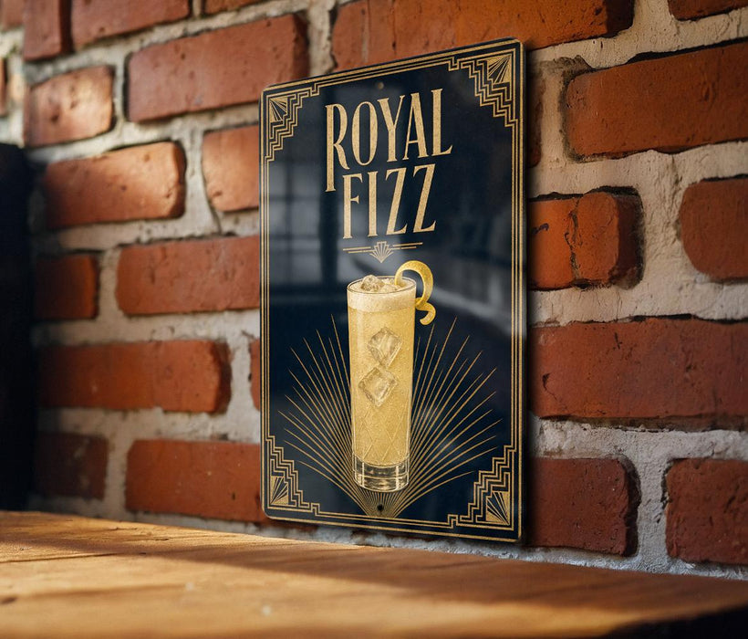 A framed poster of a glass of Royal Fizz cocktail is displayed on a brick wall.
