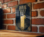 A framed poster of a glass of Royal Fizz cocktail is displayed on a brick wall.