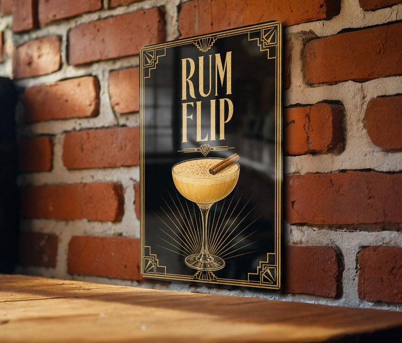 A framed poster with an illustration of a cocktail glass and the text "RUM FLIP" is displayed on a brick wall.