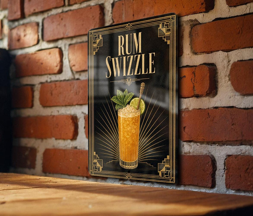 A framed poster of a cocktail called "RUM SWIZZLE" is displayed on a brick wall, featuring an illustration of a glass filled with a yellow-colored drink and garnished with a lime and a mint sprig.