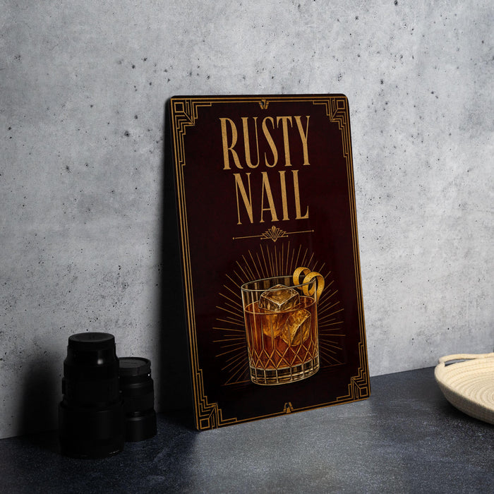 a framed advertisement for a cocktail called "RUSTY NAIL", which is a fancy drink with a glass and garnish.