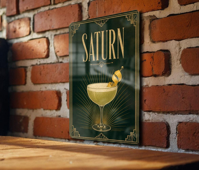 A framed poster of a cocktail glass with a cocktail in it, hanging on a brick wall.