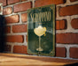 A sign for "SGROPPINO" cocktail is displayed on a brick wall, featuring an illustration of a cocktail glass with a lemon twist.