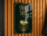 A sign that reads "Smoke Show" with an illustration of a cocktail on a green background.