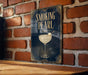 A sign with the text "Smoking Pearl" and an illustration of a cocktail glass with a pearl floating in it, mounted on a brick wall.