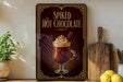 a framed advertisement for "Spiked Hot Chocolate" on a wall, with a glass mug containing a hot chocolate drink and whipped cream on top.