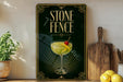 a framed poster of a cocktail glass with a garnish, placed on a shelf next to a wooden cutting board and a potted plant.